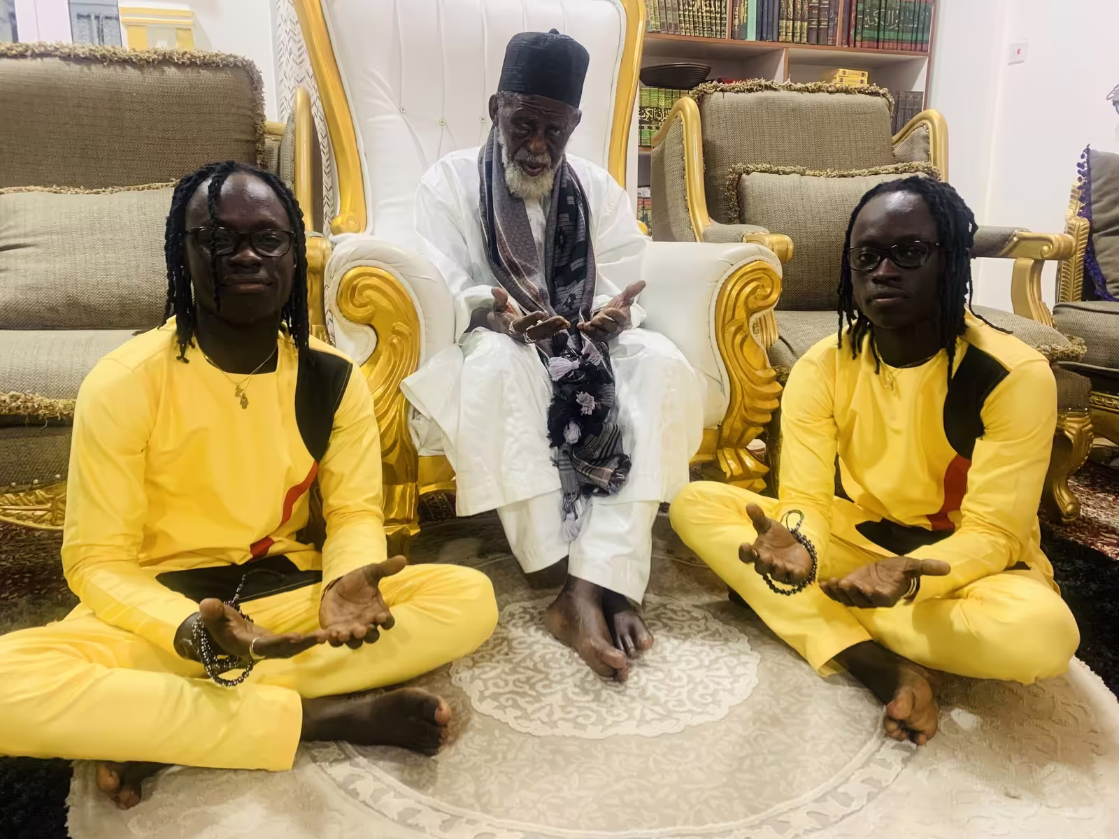 The Mystic Twins seated with an elder in prayer