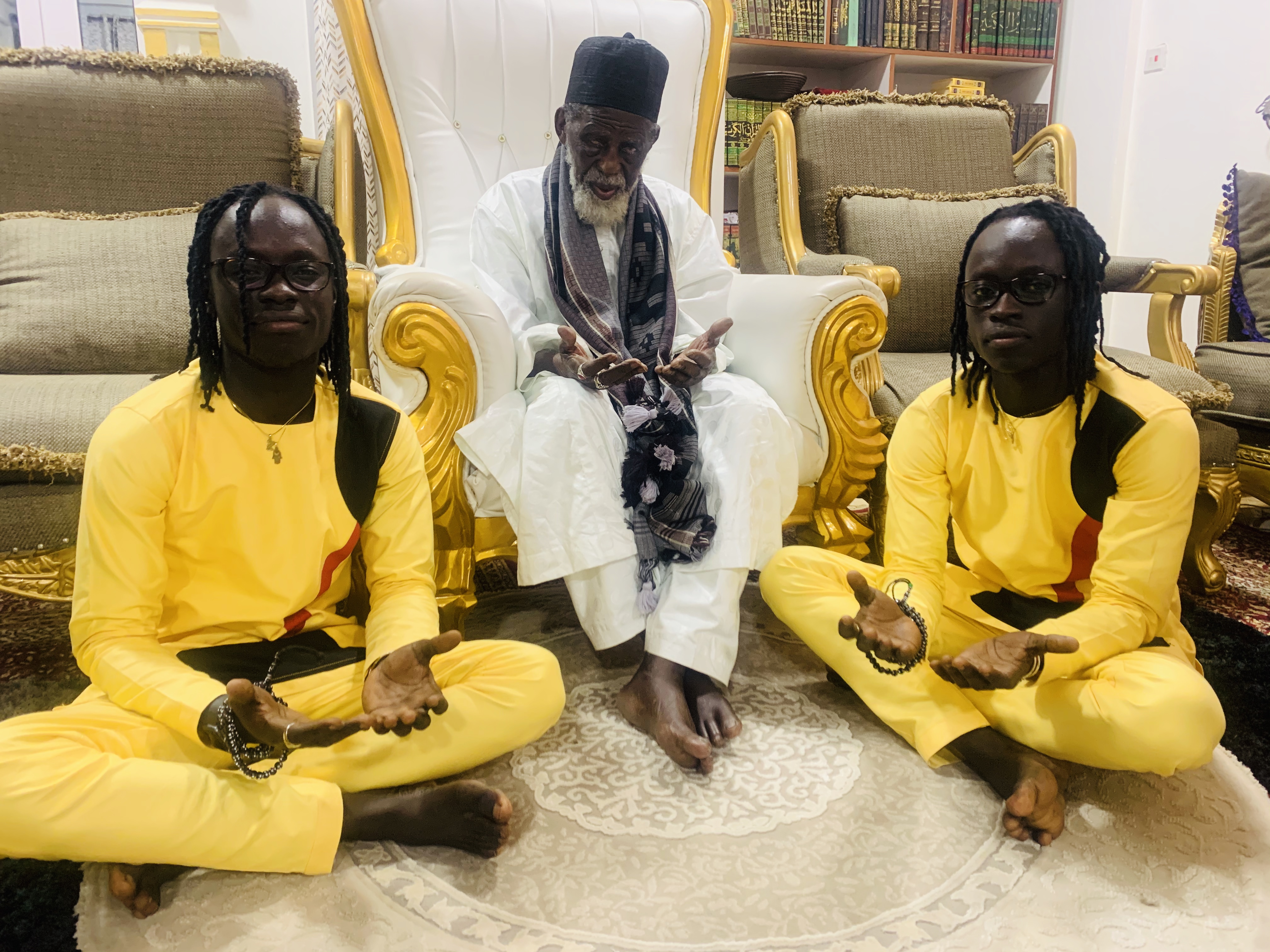 The Mystic Twins seated with an elder in prayer